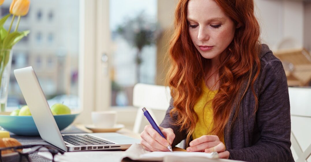 Young woman with a pencil and a laptop studying the German Präteritum