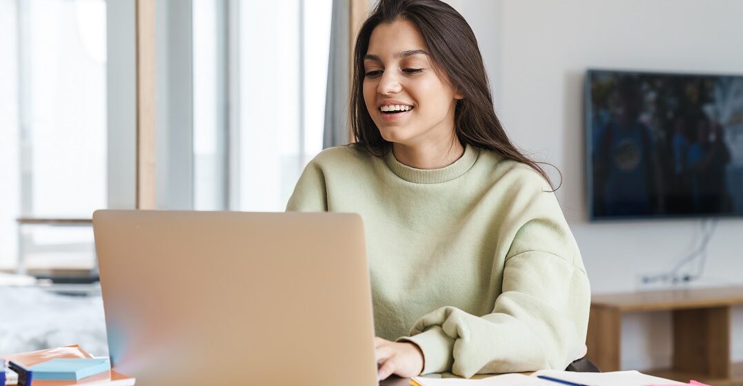 Cheerful woman in front of laptop studying the difference between too and to