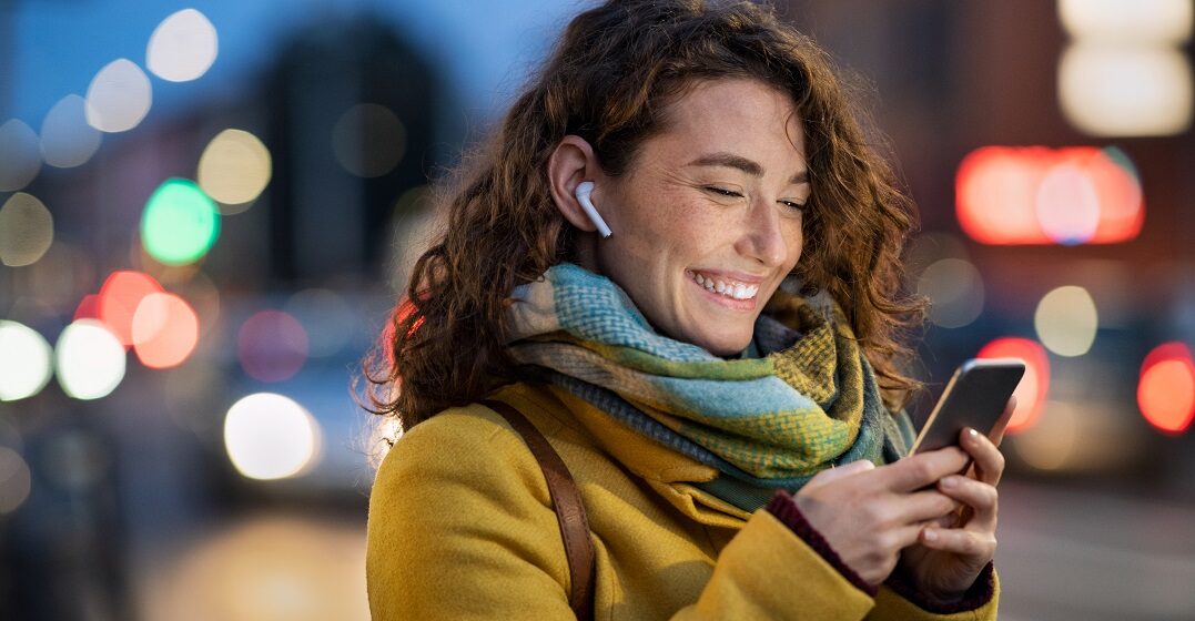 Una mujer sonriente mirando su teléfono y leyendo frases inspiradoras