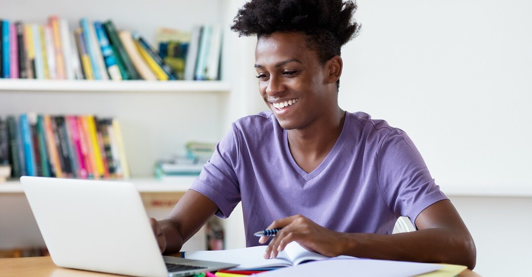 smiling man on his laptop learning the difference between cual vs que in spanish