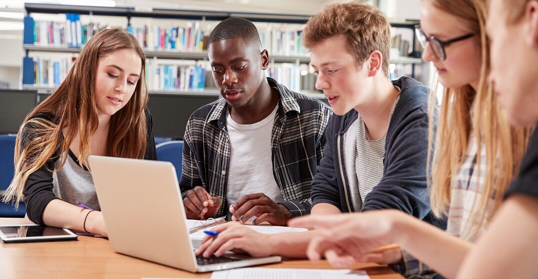 Eine Gruppe Studierende in einer Bibliothek üben das Futur 1 auf Deutsch