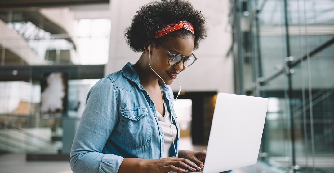 Eine junge afrikanische Frau sitzt am Laptop und lernt das Futur 2 auf Deutsch