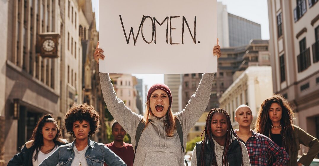 Women at a protest with a sign that says
