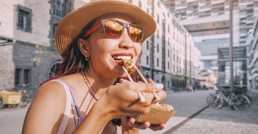 Young woman eating street food in Cologne in the honeymoon stage of culture shock