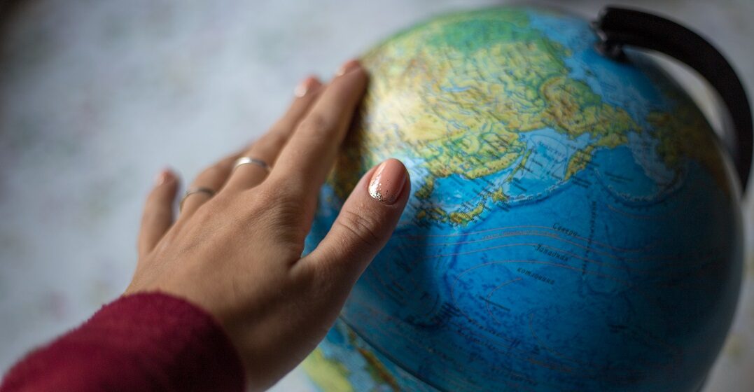 mano buscando lugares donde aprender ingles en un globo