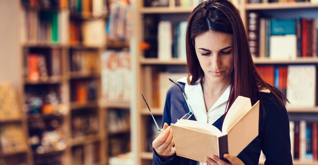 Eine Frau in einer Bibliothek liest schweizer Literatur