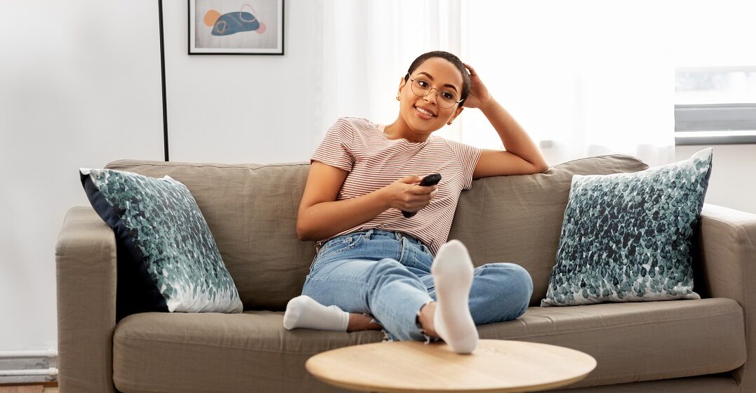 A young woman sitting on her couch watching Swiss TV channels