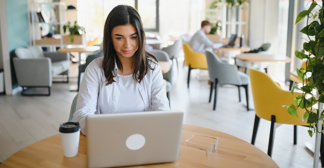 Young woman in a coworking space studying tan vs. tanto in Spanish on her laptop