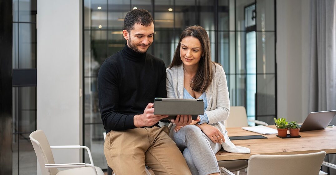 Zwei Kollegen schauen bei der Arbeit in der Schweiz zusammen auf einen Laptop