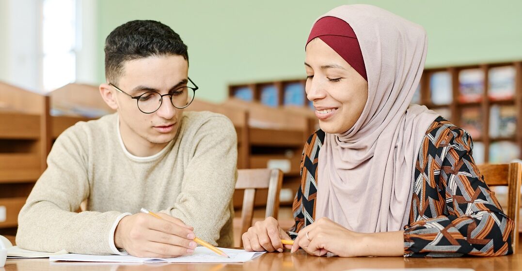 Man and woman with hijab sitting at a table, learning 6 famous French phrases and what they mean