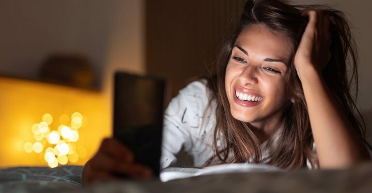 Girl in bed looking at her phone and browsing the best 5 French dating apps available