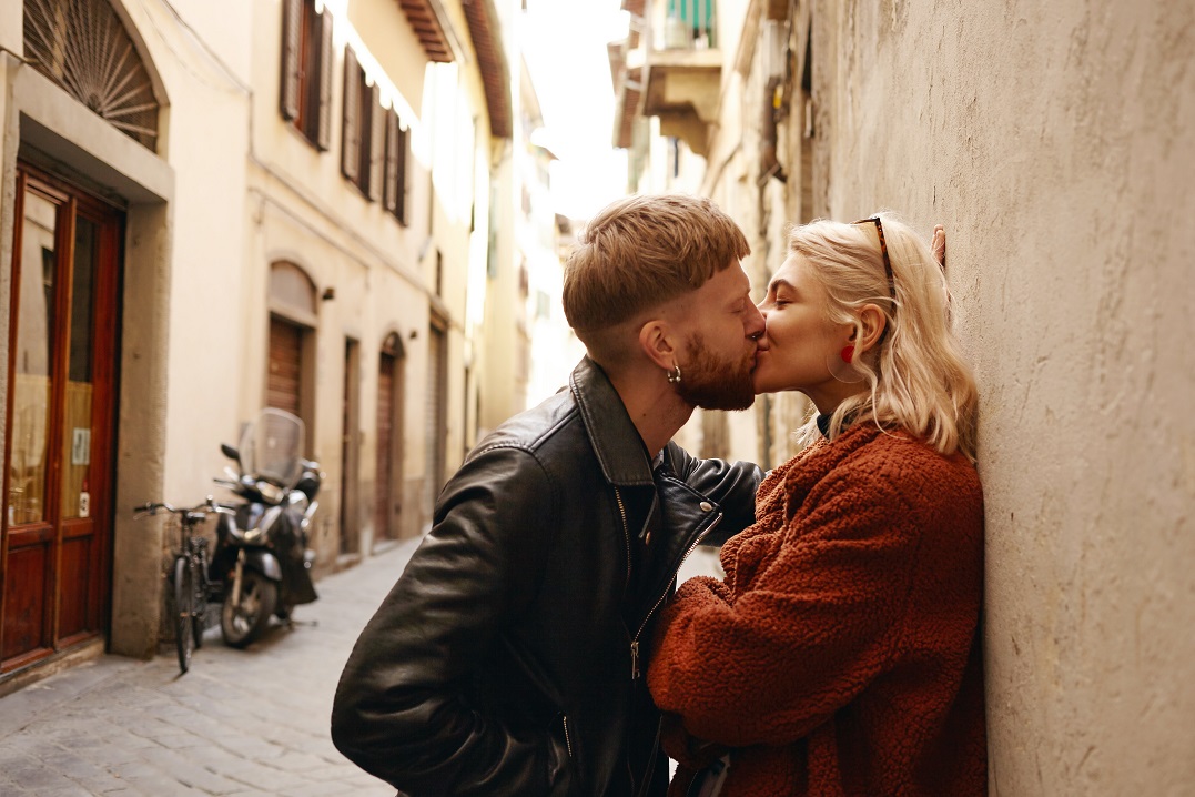 Two young people french kissing on a narrow street