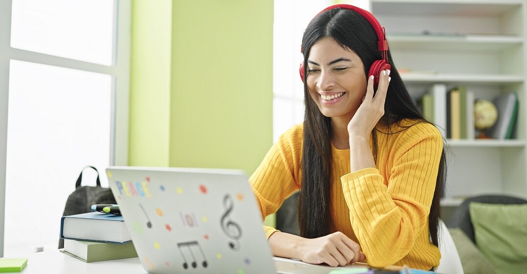 Young woman with headphones sitting at her laptop studying German suffixes
