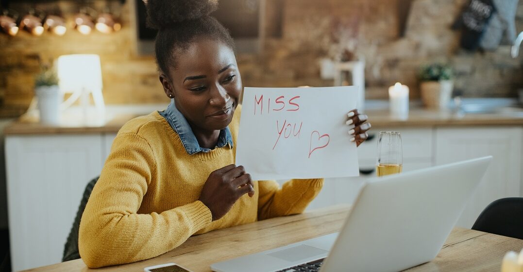 African american woman, holding a sign that read I miss you and learns how to say it in French also