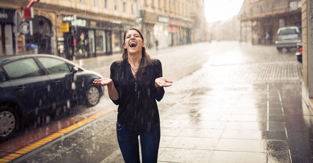 Woman standing in the rain cheerfully using Spanish weather terms to describe it