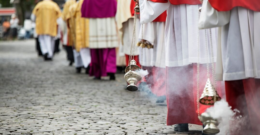 Altar boys swirl vessels with incense on a procession on Corpus Christi in Germany