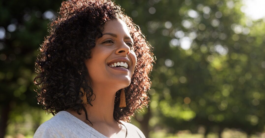 Young happy woman with curly hair as example to describe her emotions in Spanish