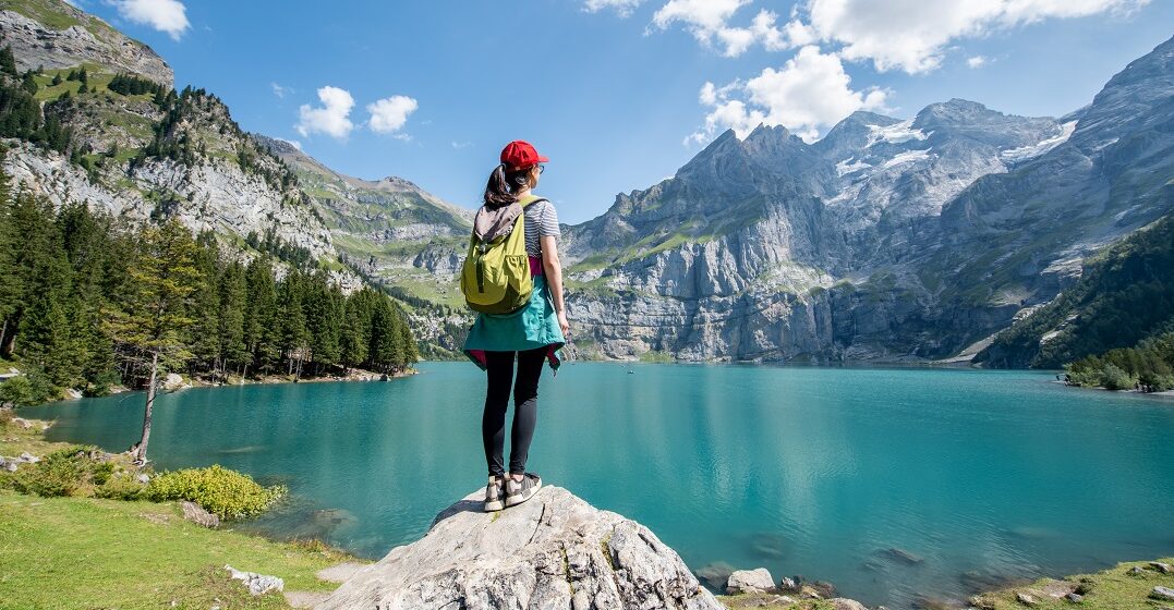 Ein Expat in der Schweiz steht vor einer Bergkulisse an einem See