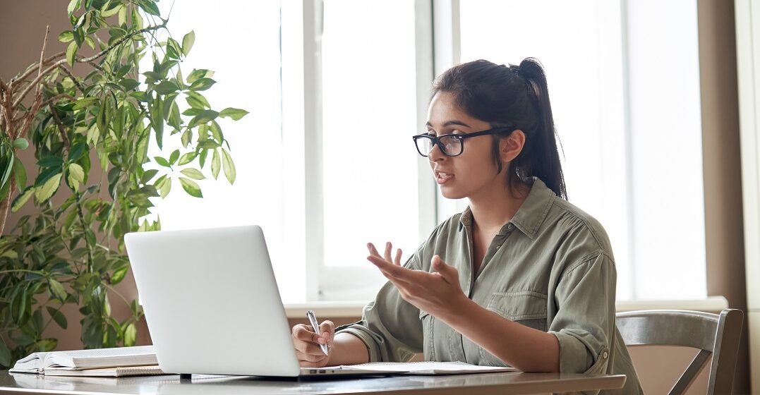 Indian woman taking an online class where she practices German pronunciation