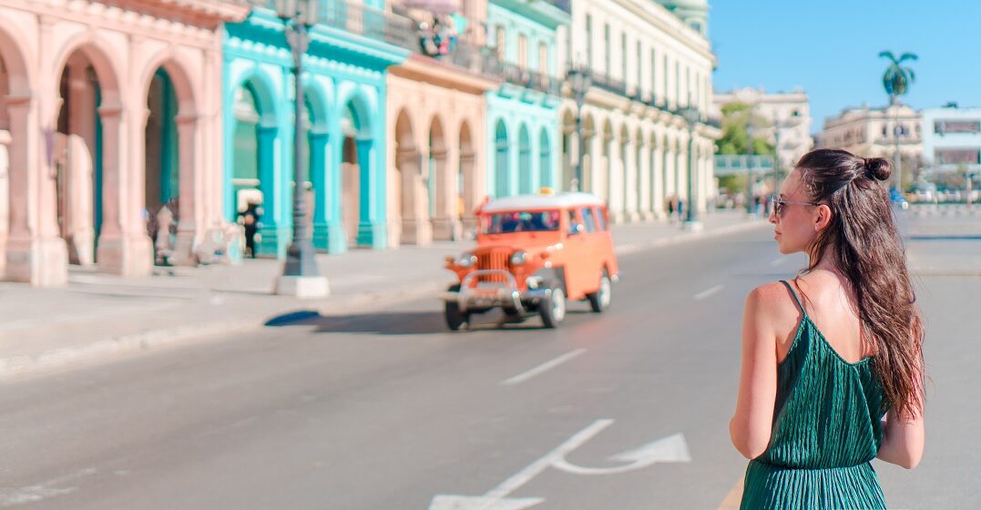 Young woman standing in front of colorful houses in Cuba considering moving there