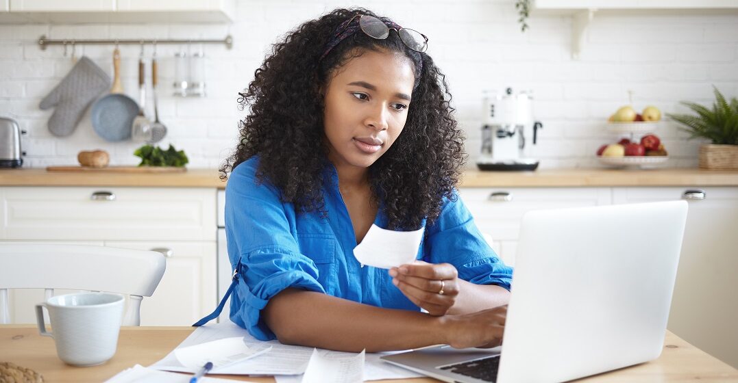 Eine junge Afroamerikanerin sitzt an ihrem Laptop und lernt die Päpositionen auf Deutsch