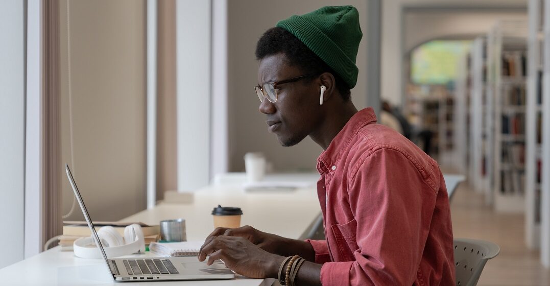 Young man focused on his laptop choosing the best Spanish language certification