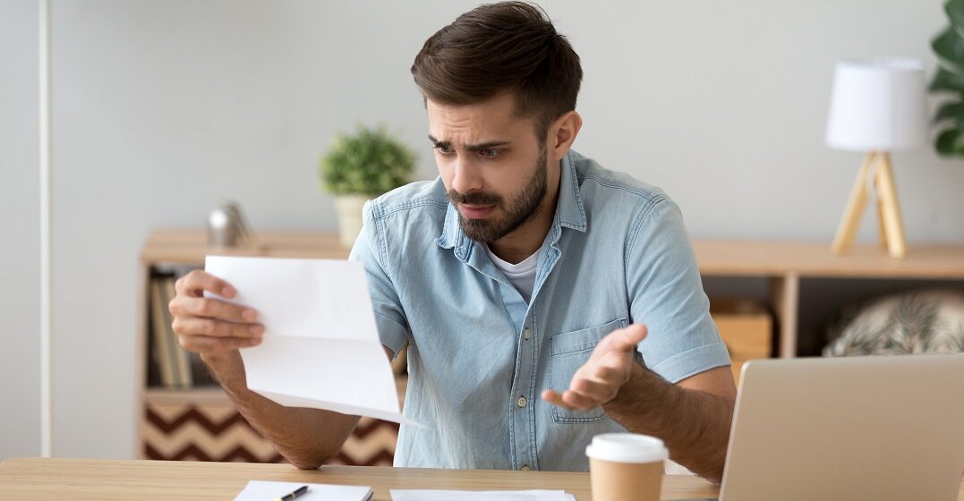 Frustrated young man holding a paper after being fired in Germany