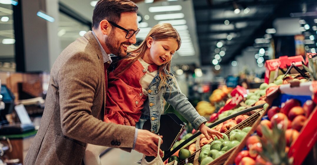 Dad and kid at the supermarket picking and learning a list of the 29 most delicious fruits in Spanish