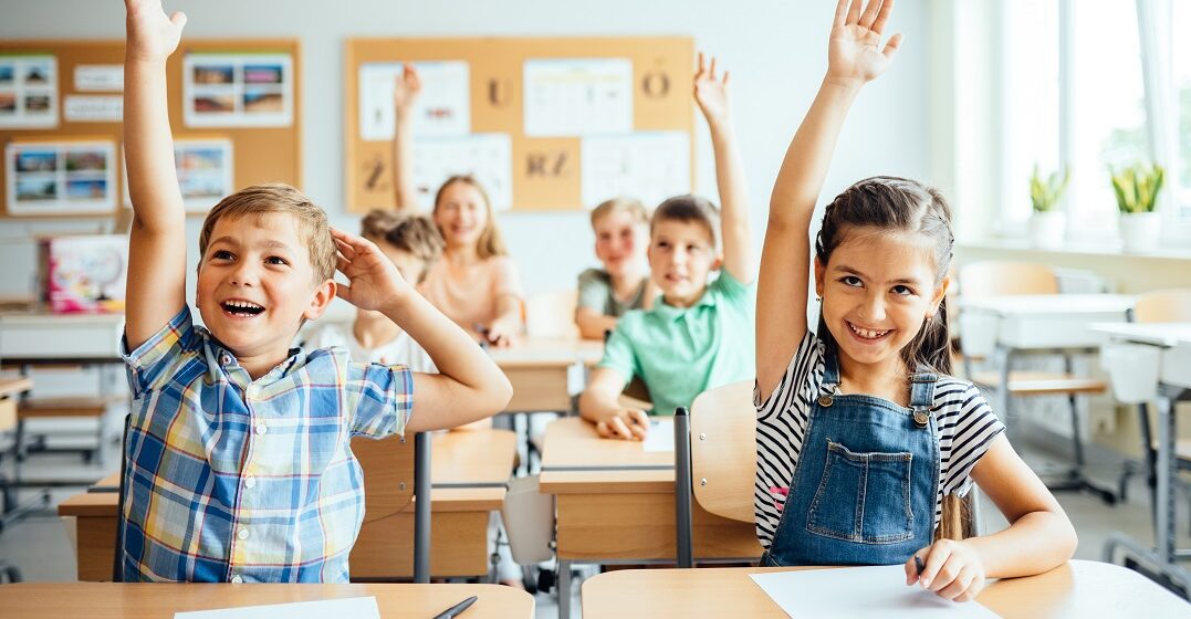 Das deutsche Bildungssystem: 2 Grundschulkinder melden sich im Klassenraum
