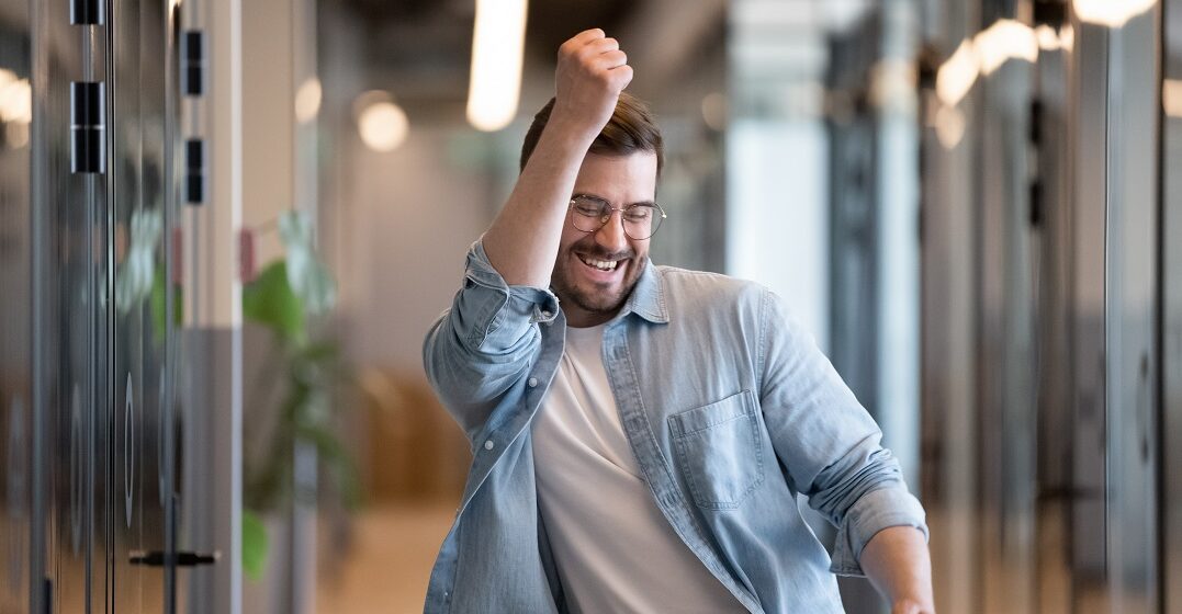 Happy young man making a winners gesture after landing an English-speaking job in Switzerland