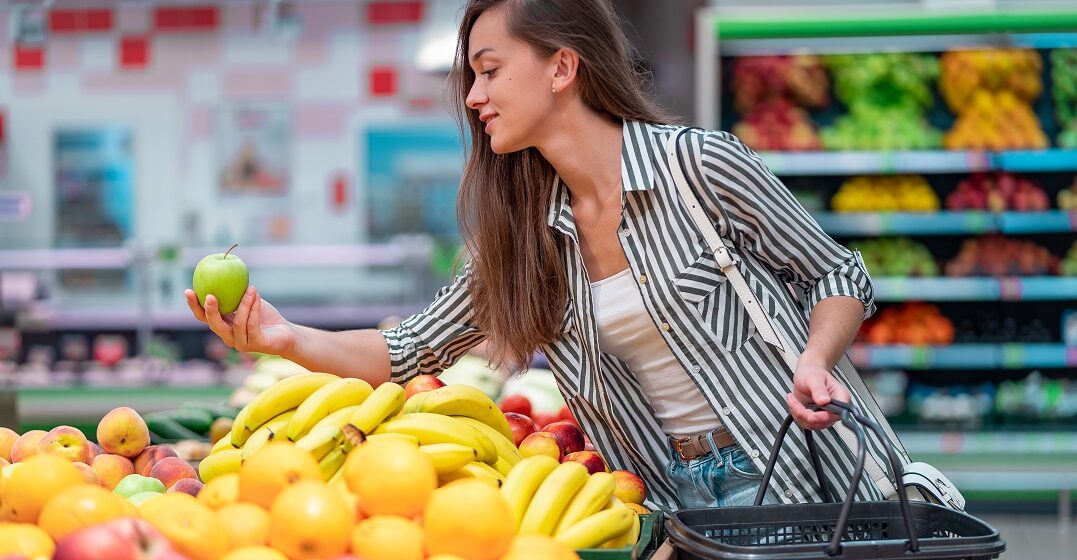 Eine Frau kauft Früchte im Supermarkt und lernt dabei Vokabeln für Obst und Gemüse auf Englisch