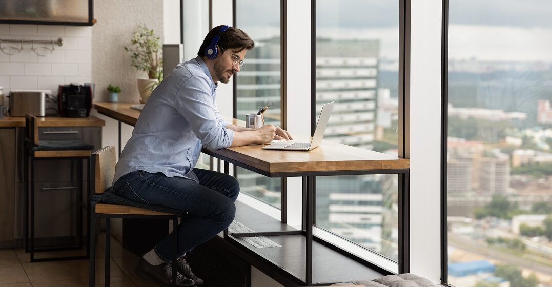 Hombre estudiando en un escritorio alto con una ventana delante el pasado perfecto en inglés