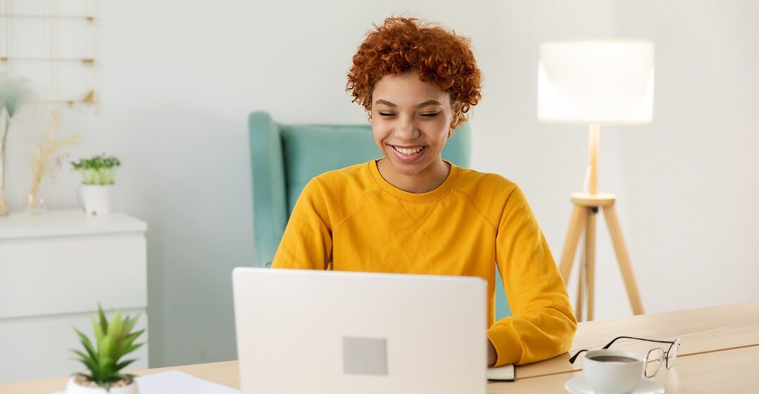 EIne junge Afroamerikanerin sitzt am Laptop und lernt die Nominalisierung von Verben auf Deutsch