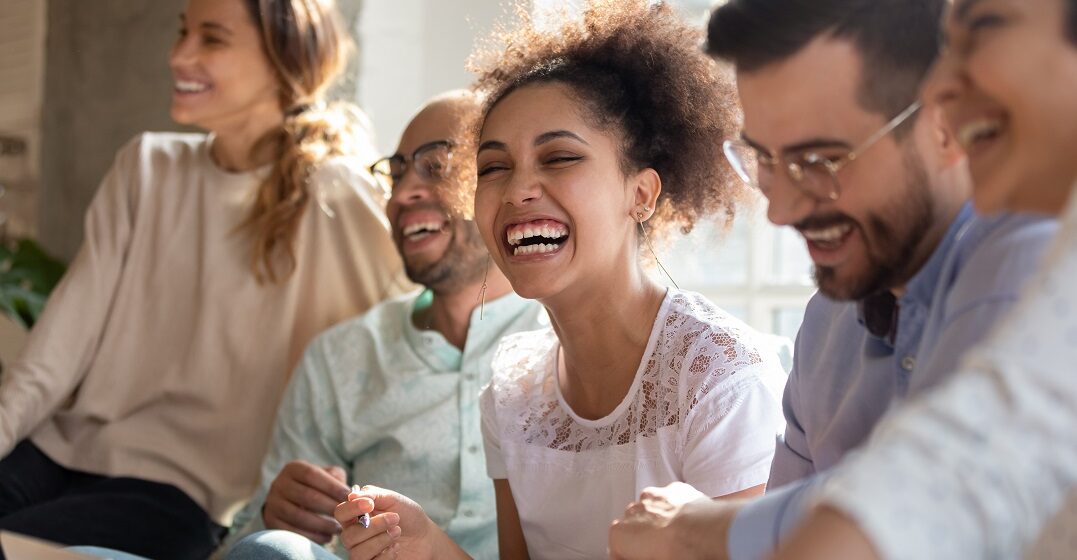 Fünf Freunde sitzen nebeneinander und lachen über lustige Schweizer Wörter