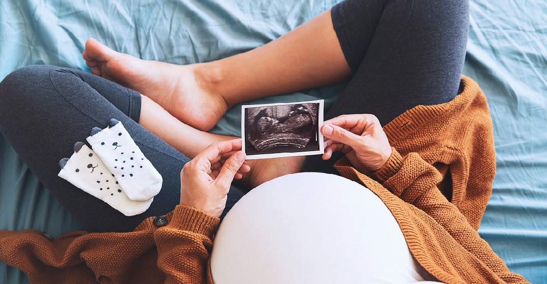 Pregnant woman holding an ultrasoun picture and planning her maternity leave in Switzerland