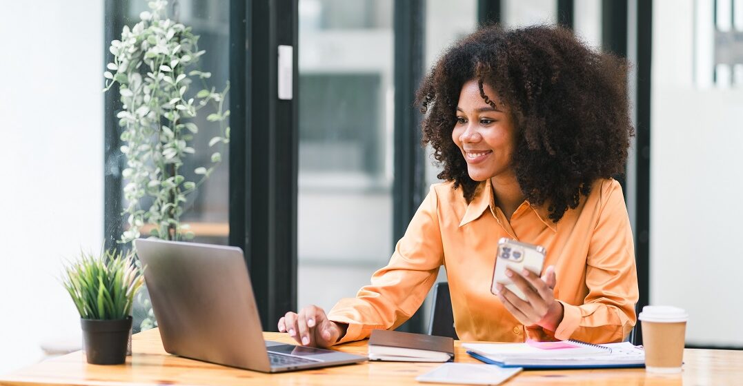 Eine Afroamerikanerin sitzt an ihrem Laptop und lernt Schweizerdeutsch