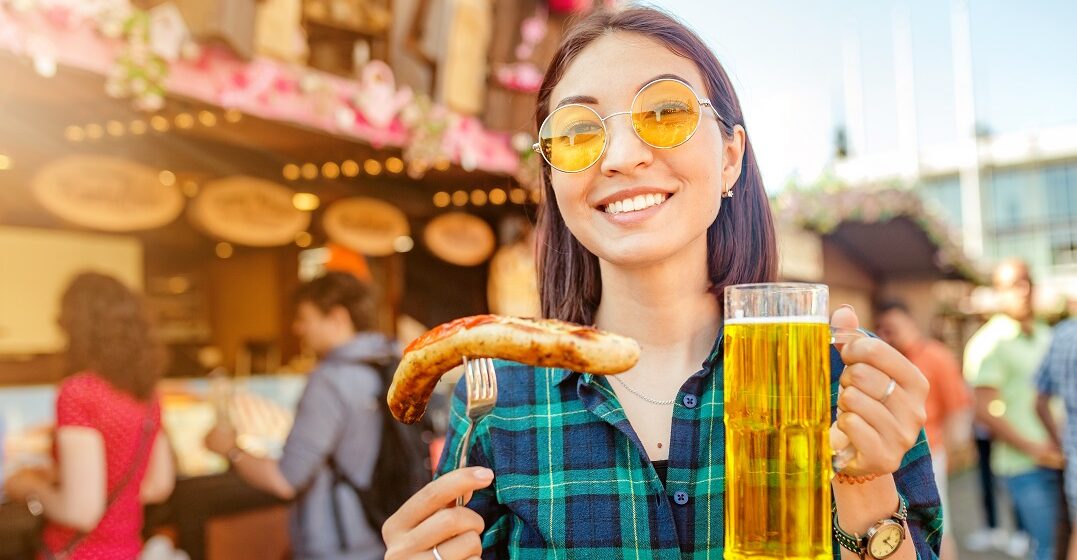 Eine junge Frau ist ein typisch deutsches Gericht auf einer Kirmes: Bratwurst mit Bier