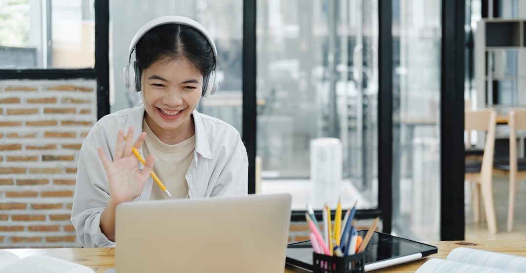 Junge Frau sitzt am Laptop und lernt das deutsche Verb 
