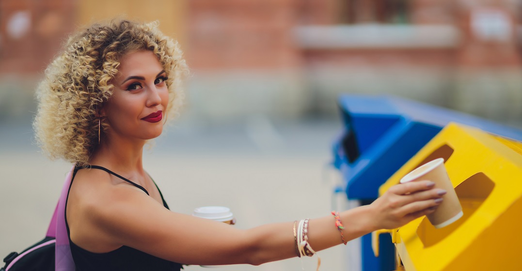 A woman using a yellow recycling bin in Germany