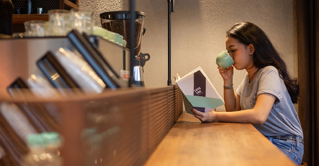 Eine junge Frau sitzt an einem Schreibtisch, liest in einem Buch und lernt den Unterschied zwischen 