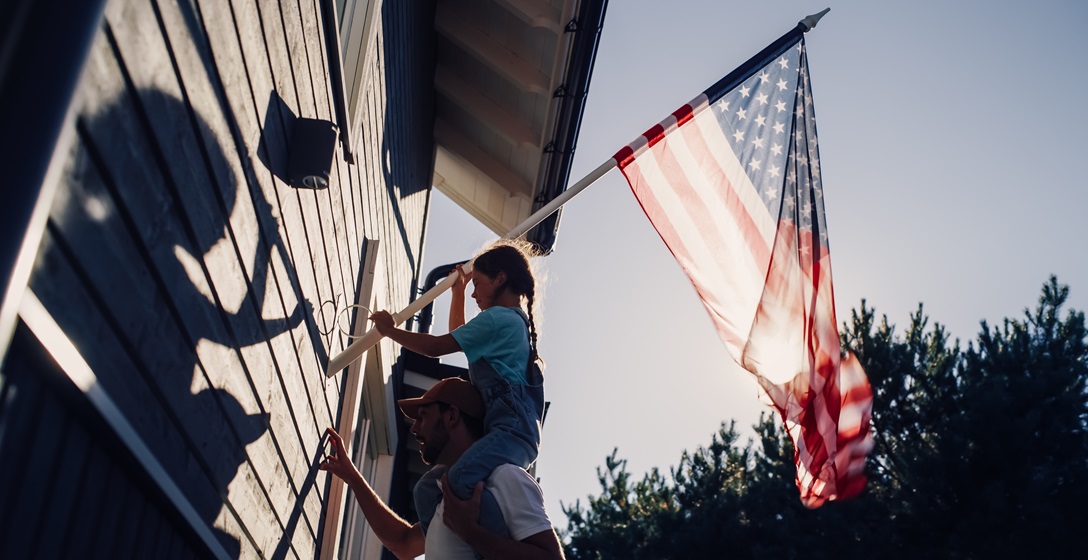 A German American father and his daughter are hanging up an American flag at their house