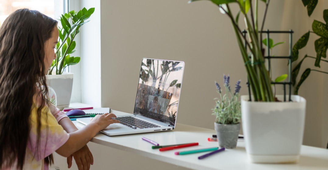 Young woman sits at her laptop writing a text using German quotation marks
