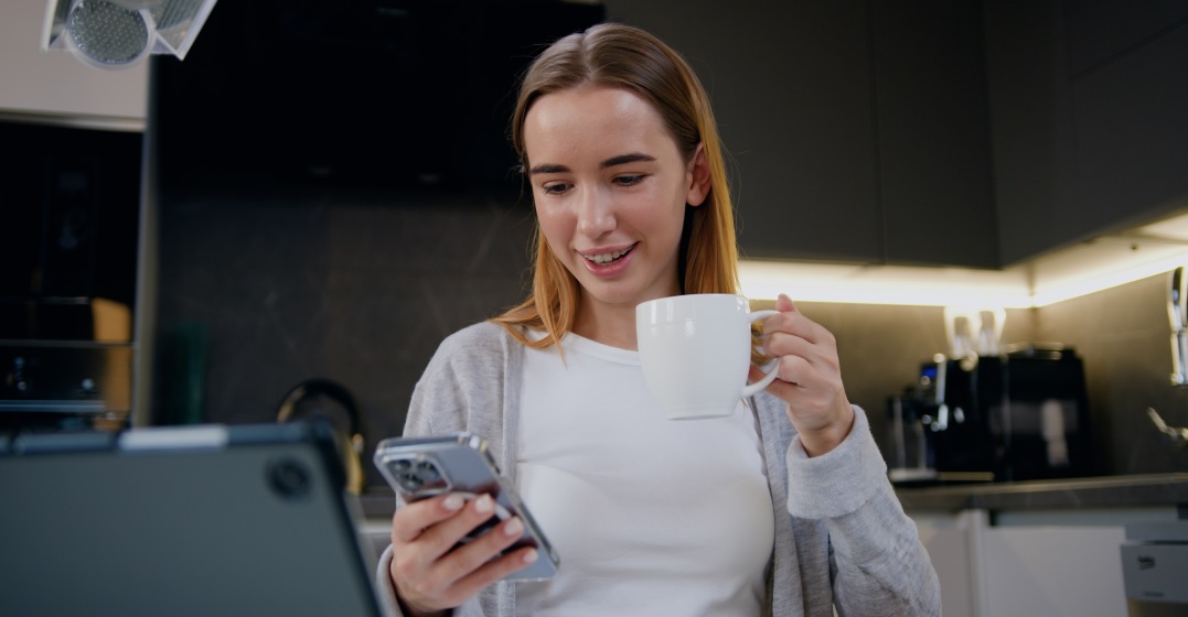 A girl holding a cup of coffee and her smartphone reading how to use zu in German