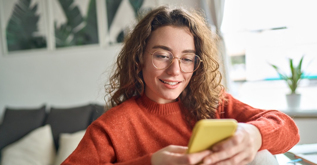 Young smiling woman looking at her smartphone