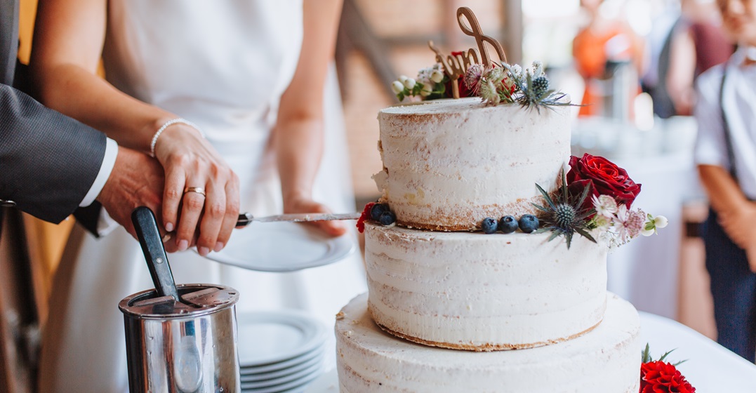A couple cutting the wedding cake together- a German wedding tradition