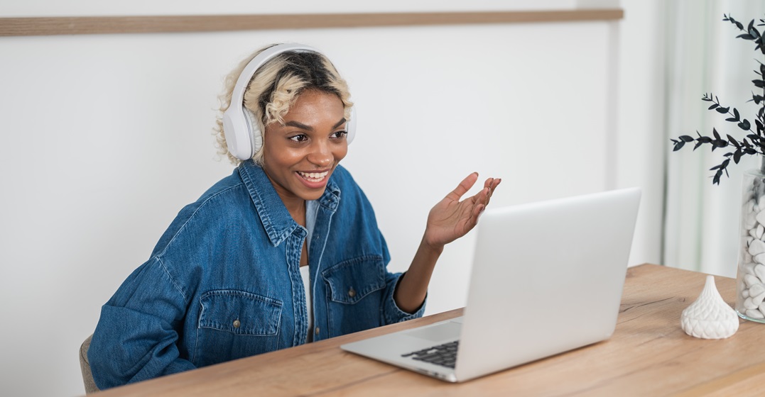 Happy student sitting at her laptop in an online language lclass learning about the past perfect in German