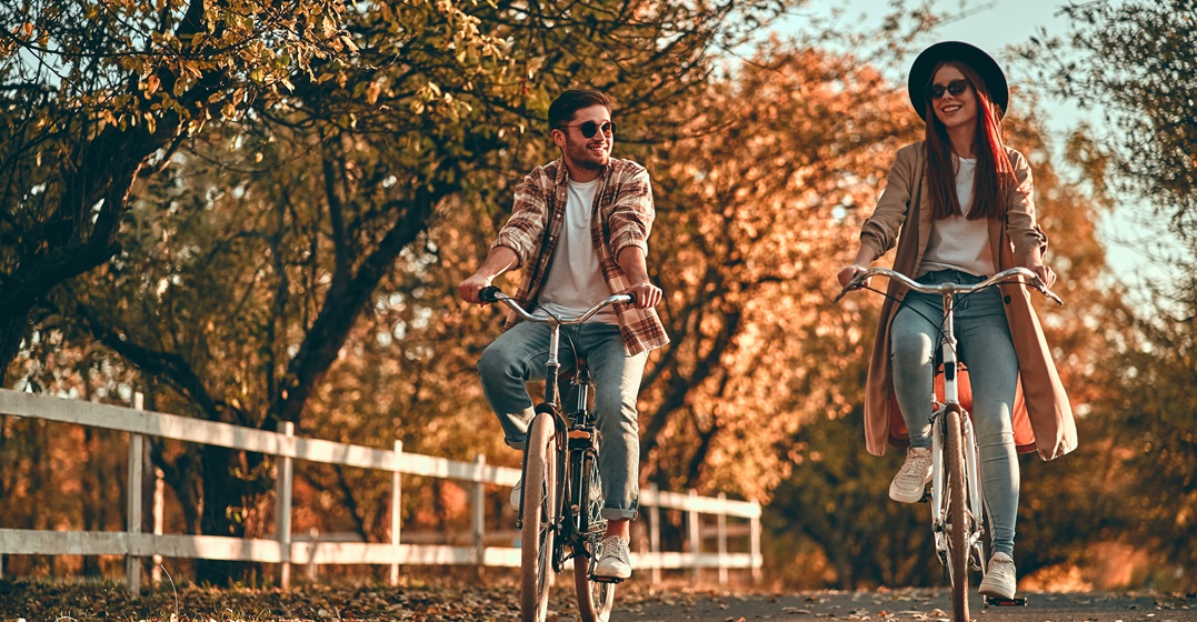 Young couple cycling in autumn studying the seasons in German