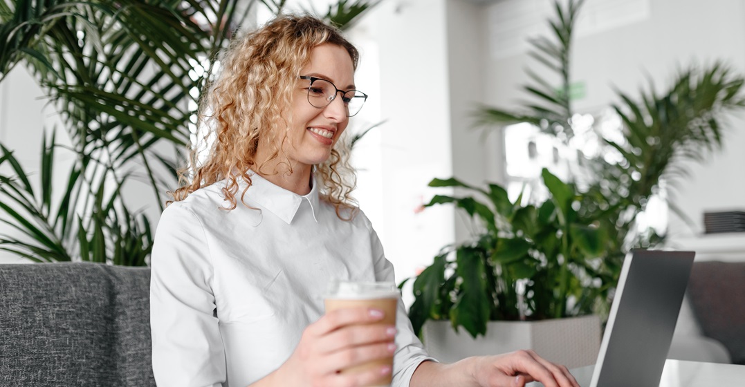 Young woman at her laptop with a coffee studying the contractions in Spanish