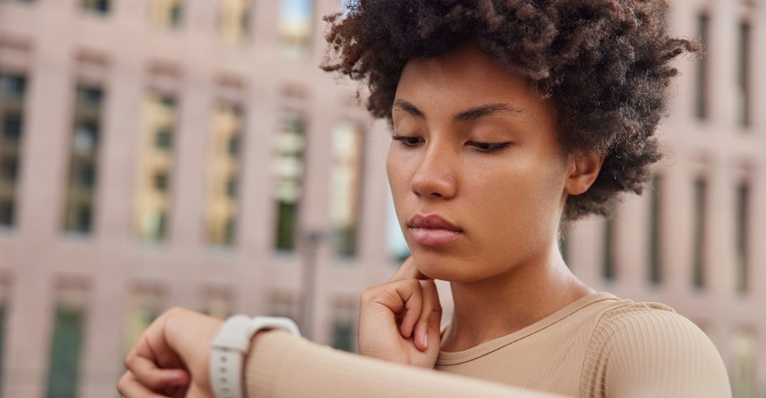 Young African woman looking at her watching learning the times of day in German