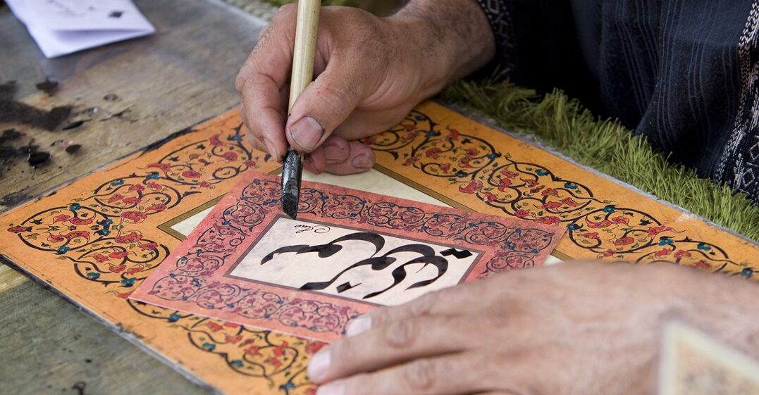 A,Man,Writing,A,Name,With,Traditional,Arab,Characters,In